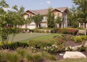 Thumbnail 19 of 23 - Meticulously maintained grounds with mature trees surround the soft tan paint and brick exterior apartment homes at Villas at Carrington Square Apartments, Overland Park, KS 66221