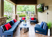 Thumbnail 20 of 26 - A patio with blue couches and pillows, a coffee table, and a flat screen TV mounted on the wall.