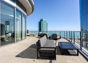 Thumbnail 25 of 42 - A black sofa and table are on a balcony with a view of the city.