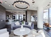 Thumbnail 20 of 42 - A modern living room with a grey sofa, a white coffee table, and a chandelier.