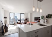 Thumbnail 8 of 42 - A modern kitchen with a large island and a view of the city.