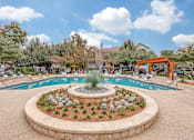 Thumbnail 19 of 30 - A pool surrounded by a circular flower bed with a palm tree in the middle.
