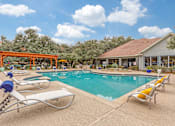Thumbnail 20 of 30 - A pool with sun loungers and a building in the background.