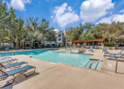 Thumbnail 20 of 23 - Apartments in North Austin, TX for Rent - Sycamore Springs - Sparkling Swimming Pool with Lounge Chairs, Umbrellas, Elevated Spa, Grill Station, and Beautiful Landscaping