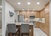 Thumbnail 4 of 25 - a kitchen with wooden cabinets and an island with two chairs