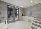 Thumbnail 16 of 25 - a bathroom with grey tiles and a glass door leading to a patio