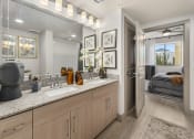Thumbnail 8 of 35 - a bathroom with a sink and a mirror and a door to a bedroom