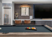 Thumbnail 21 of 35 - a pool table and a tv in a room with a brick wall