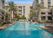 Thumbnail 24 of 35 - a swimming pool with palm trees and a building in the background