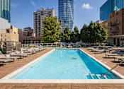 Thumbnail 32 of 42 - A large swimming pool with a blue tinted water surrounded by a wooden deck and lounge chairs.