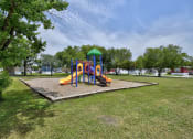Thumbnail 8 of 39 - a playground with a swing set and sandbox in the middle of a grassy area with trees