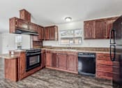 Thumbnail 15 of 22 - A kitchen with wooden cabinets and black appliances.