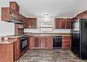 Thumbnail 18 of 22 - A kitchen with wooden cabinets and black appliances.
