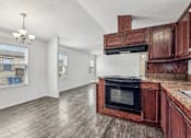 Thumbnail 16 of 22 - A kitchen with wooden cabinets and a black oven.