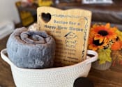 Thumbnail 5 of 8 - A bowl with a rolled-up grey towel, a recipe book, and a small jar on a wooden surface.