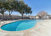 Thumbnail 15 of 39 - A large outdoor swimming pool surrounded by trees.