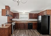 Thumbnail 37 of 39 - A kitchen with wooden cabinets and black appliances.