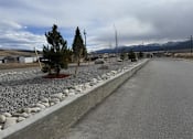 Thumbnail 3 of 8 - A road with a gravel area on the side and a few trees.