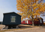 Thumbnail 5 of 22 - a black house with a red house behind it next to a tree at Country Lane, Cheyenne, WY