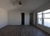 Thumbnail 11 of 20 - an empty living room with wood floors and a ceiling fan at Horizon MHC, Rock Springs, 82901