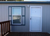 Thumbnail 6 of 20 - the front door and window of a house with a wooden deck at Horizon MHC, Rock Springs