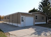 Thumbnail 8 of 9 - the front of the home has a driveway and a white garage door at Kimberly Village, Cheyenne, WY, 82007