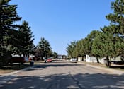 Thumbnail 4 of 9 - a street in a neighborhood with trees and cars on it at Kimberly Village, Cheyenne, WY