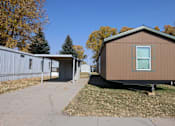 Thumbnail 1 of 7 - the exterior of a tiny house with a driveway and a shed at Mobile Home Village, Cheyenne, WY, 82001