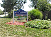 Thumbnail 1 of 13 - A sign for Maple Grove Assisted Living is shown in front of a fence and some trees.