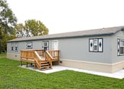 Thumbnail 2 of 4 - A grey house with a wooden deck in front.