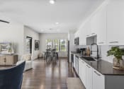 Thumbnail 4 of 50 - a kitchen and living room with white cabinets and a black counter top