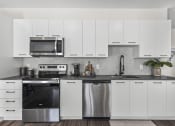 Thumbnail 2 of 50 - a white kitchen with stainless steel appliances and white cabinets