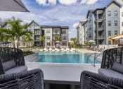 Thumbnail 27 of 50 - a swimming pool with lounge chairs in front of an apartment building