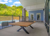 Thumbnail 16 of 76 - a ping pong table on the patio of a building with a pool in the background at The Lodge at Overland, Rochester, Minnesota