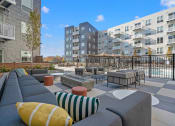 Thumbnail 29 of 57 - an outdoor lounge area with couches and tables with buildings in the background