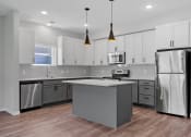 Thumbnail 55 of 76 - a kitchen with white cabinets and a gray island with a white countertop at The Lodge at Overland, Rochester, MN