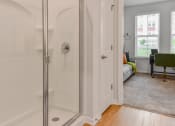 Thumbnail 11 of 42 - a bathroom with a shower and a living room with a couch at The View on Collins, Lansing, MI