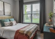 Thumbnail 7 of 79 - a bedroom with a bed and a large window at The Commons at Rivertown, Grandville, MI