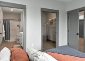 Thumbnail 5 of 79 - a bedroom with a bed and a bathroom with a closet at The Commons at Rivertown, Grandville, Michigan