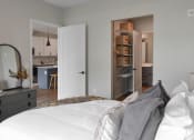 Thumbnail 10 of 76 - a bedroom with a bed and a closet and a kitchen at The Lodge at Overland, Rochester, MN