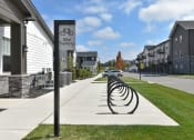 Thumbnail 28 of 79 - a bike parking sign on the sidewalk in front of a row of houses at The Commons at Rivertown, Grandville, 49418