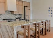 Thumbnail 45 of 83 - A kitchen with a marble countertop and wooden bar stools.