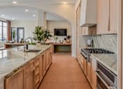 Thumbnail 40 of 83 - A kitchen with wooden cabinets and a marble countertop.
