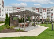 Thumbnail 38 of 42 - an outdoor patio with a table and chairs in front of an apartment building  at The View on Collins, Lansing, Michigan