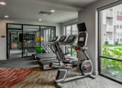 Thumbnail 31 of 42 - a gym with cardio machines and a large window at The View on Collins, Michigan, 48910