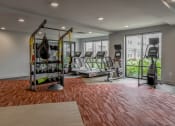 Thumbnail 34 of 42 - a gym with treadmills and weights on a brick floor at The View on Collins, Lansing, Michigan