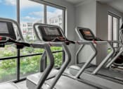 Thumbnail 32 of 42 - a gym with cardio machines and a view of the city at The View on Collins, Lansing, 48910
