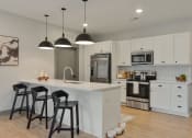 Thumbnail 1 of 79 - a kitchen with white cabinets and a white island with three stools at The Commons at Rivertown, Grandville, MI, 49418