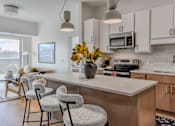 Thumbnail 71 of 83 - A kitchen with a white countertop and a vase of yellow flowers on it.