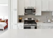 Thumbnail 4 of 57 - a kitchen with white cabinets and a stove and microwave